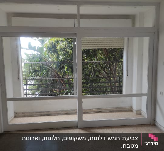 חלון גדול עם מסגרת לבנה, נוף של צמחייה בחוץ